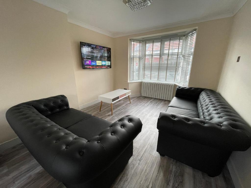 sala de estar con muebles de cuero negro y sofá en Modern 4-bedroom entire house with Garden en Uxbridge