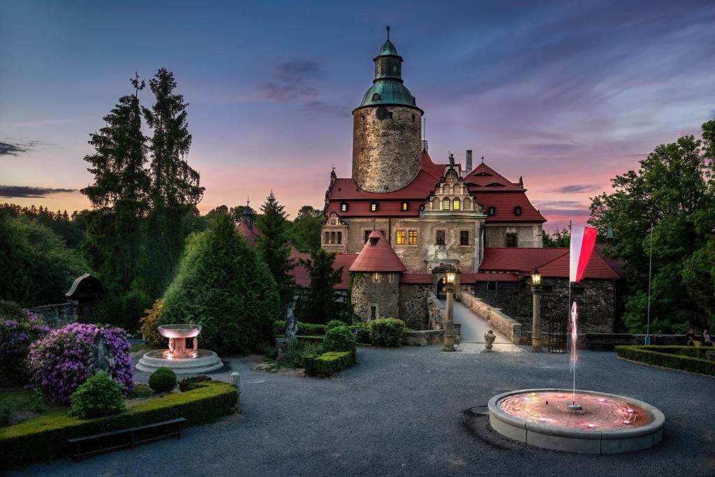 an old castle with a clock tower in a garden at Zamek Czocha in Leśna