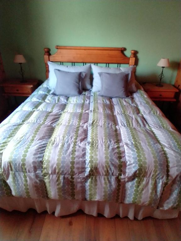 1 cama con edredón a rayas y 2 mesitas de noche en Allegra, casa de descanso en San Martín de los Andes