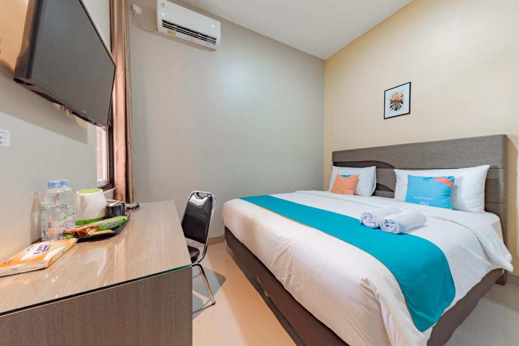 a bedroom with a bed and a desk with a tv at Sans Hotel Berau Square in Tanjungredep