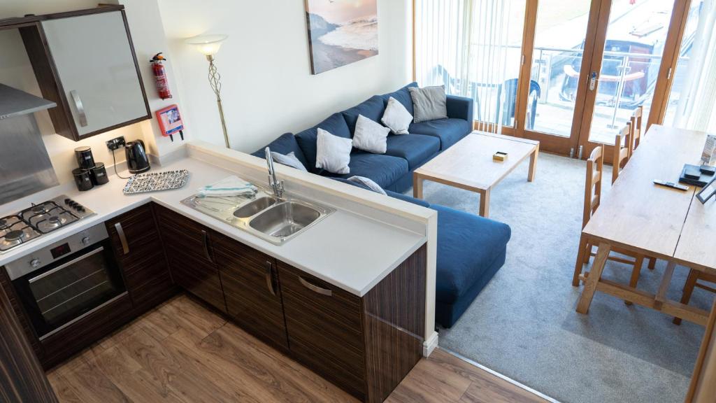 eine Küche und ein Wohnzimmer mit einem blauen Sofa in der Unterkunft Tewitfield Marina in Carnforth