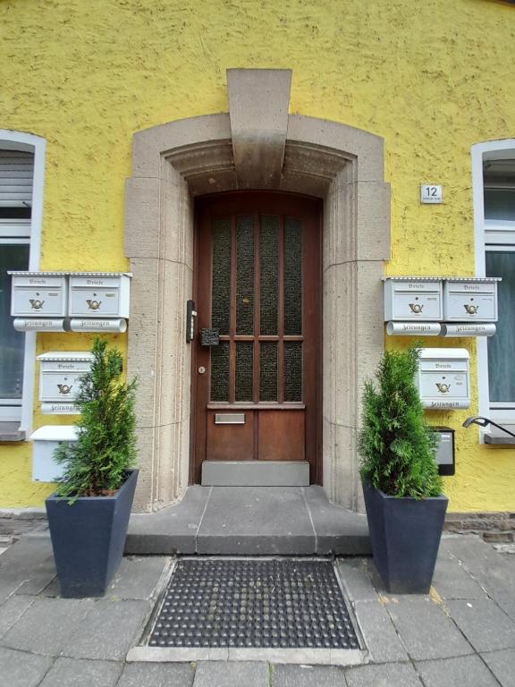 un edificio giallo con una porta marrone e due piante di KOBLENZ O&O Apartment a Coblenza