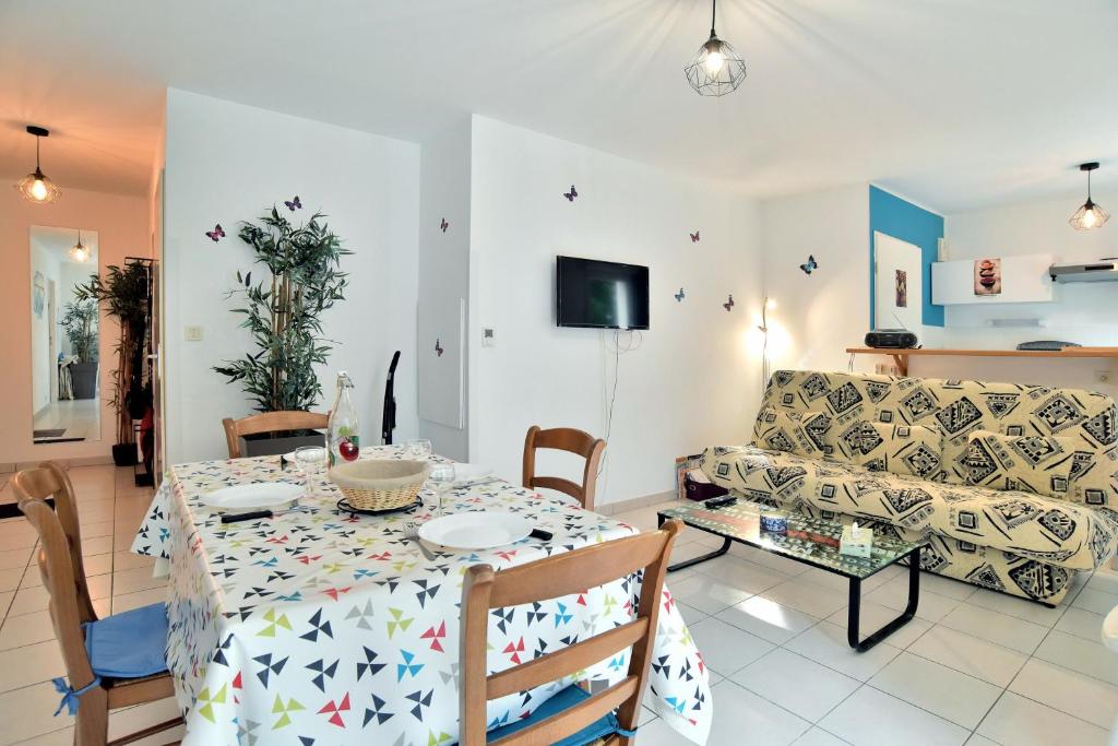 ein Wohnzimmer mit einem Tisch und einem Sofa in der Unterkunft Butterfly - Appartement avec jardin in Miniac-Morvan
