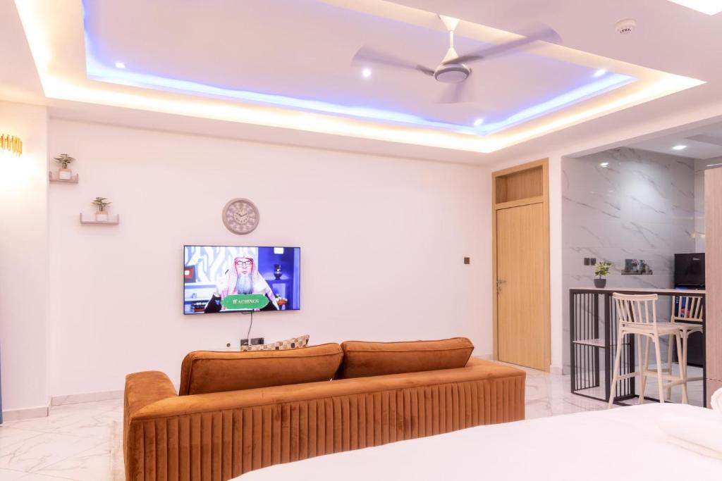 een woonkamer met een bank en een televisie aan het plafond bij Executive Studio Apartment, East Airport in Accra