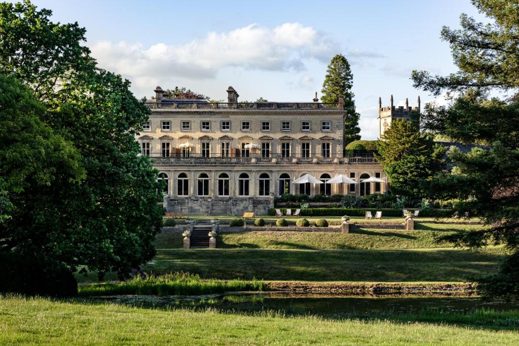 Cowley Manor Experimental في تشلتنهام: بيت ابيض كبير وبه حديقة واشجار