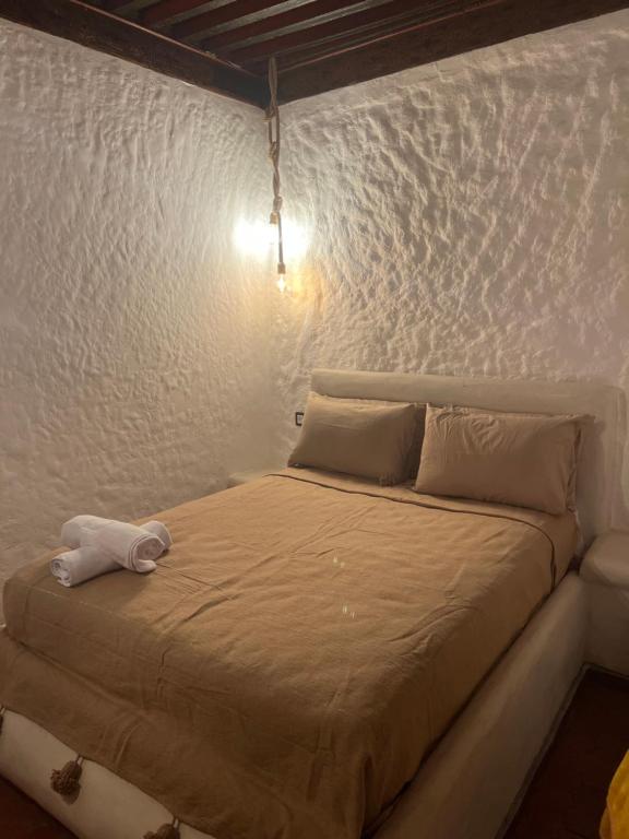 Cama en habitación con pared blanca en Riad Mauritania, en Chefchaouen