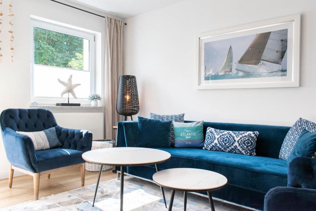 een woonkamer met een blauwe bank, 2 stoelen en een tafel bij Ferienhaus Das Kleine Strandhaus Scharbeutz in Scharbeutz