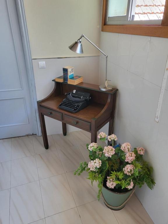 a desk with a keyboard and a lamp and flowers at CASA MARUXA pensión in Pontevedra