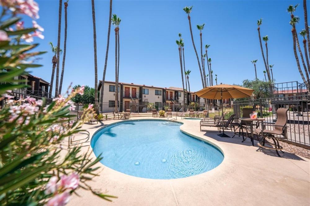una piscina con mesas, sillas y una sombrilla en 214 Fully Furnished 1BR Suite-Outdoor Pool, en Scottsdale