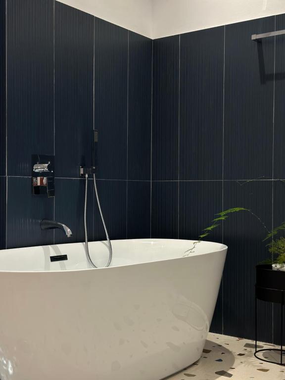 uma banheira branca na casa de banho com azulejos pretos em Hotel Restaurant Natyra e Qetë em Lezhë