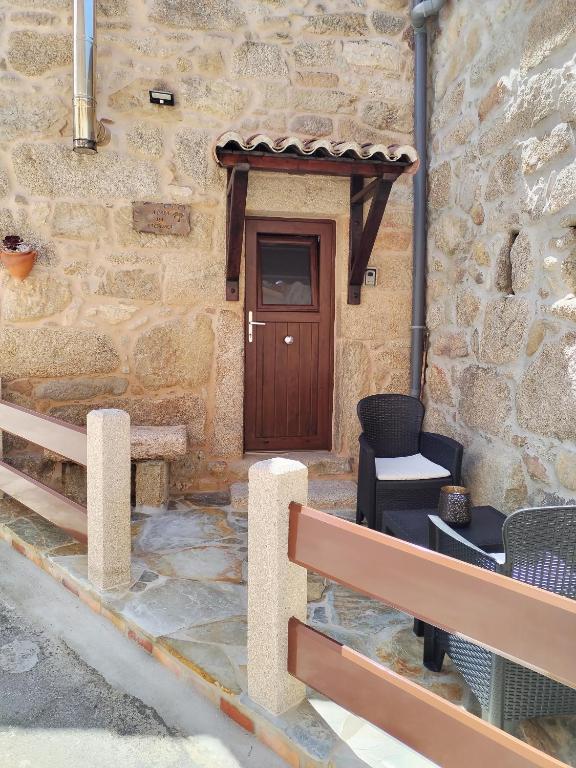 a stone building with a wooden door and chairs at A CASIÑA DA PALMERA in Vilar