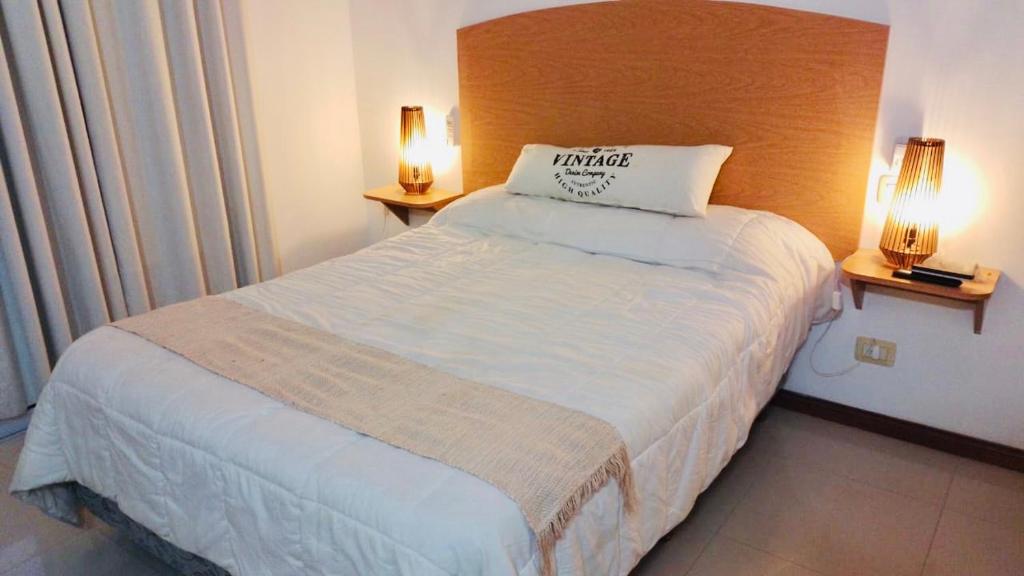 a bed in a hotel room with two lamps at Depto Av del Sol in Merlo