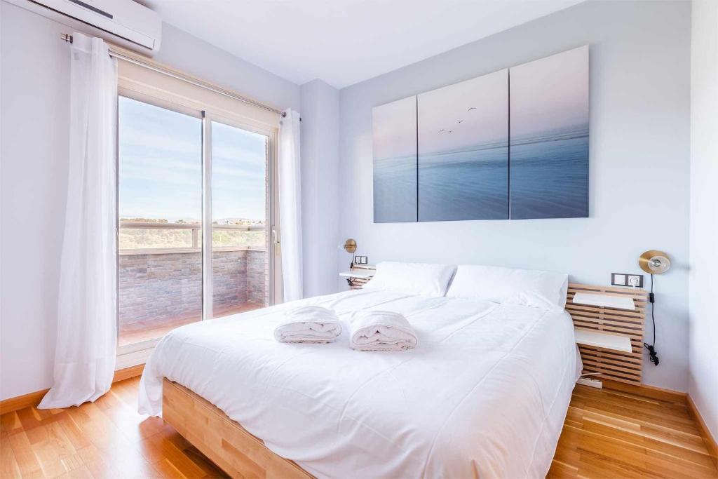 1 dormitorio con 1 cama blanca grande y 2 toallas en A&N La Vega 13, en Torre del Mar