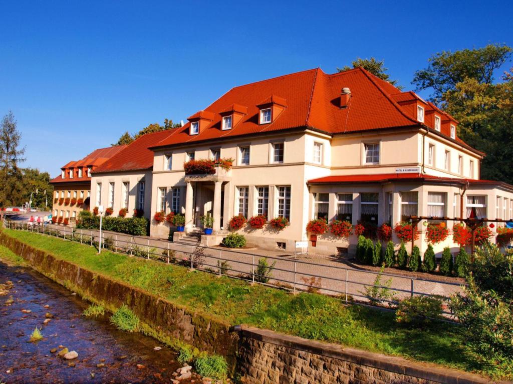 ein großes weißes Haus mit rotem Dach in der Unterkunft Hotel Sächsisches Haus in Berggiesshübel
