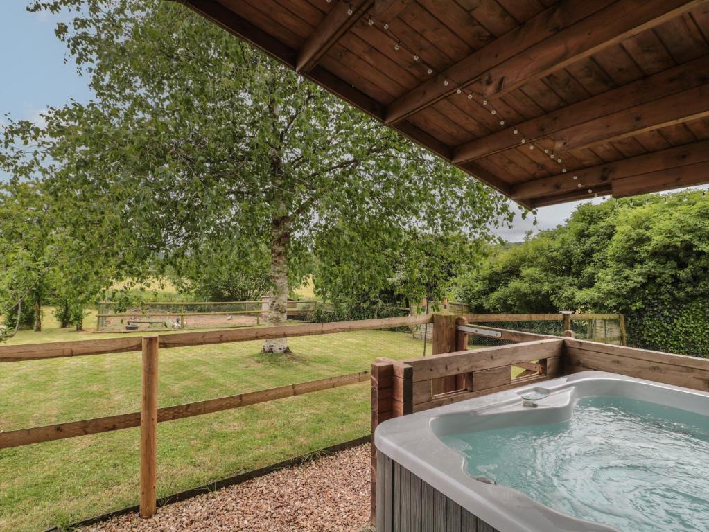 een hot tub op een terras met een hek bij Pigsfoot Lodge in Tiverton