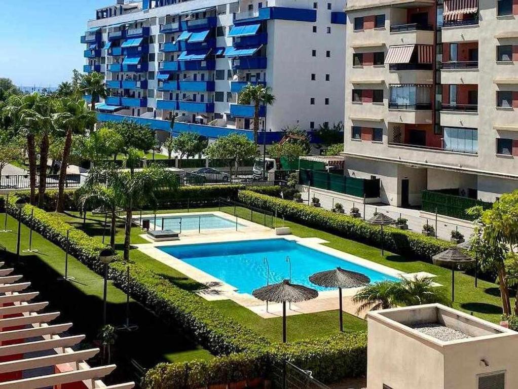a swimming pool with umbrellas in front of a building at A&N Spacious Family Retreat with Pool & Parking in Torre del Mar