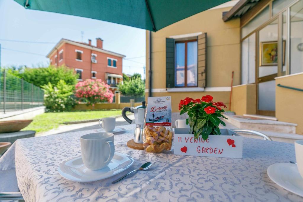 a table with a cup of coffee and a vase of flowers at 11 Venice Garden Private garden parking free in Marghera