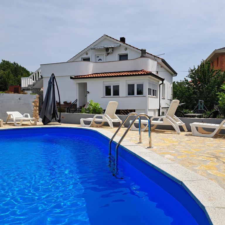 a swimming pool in front of a house at Apartman Dadić in Malinska