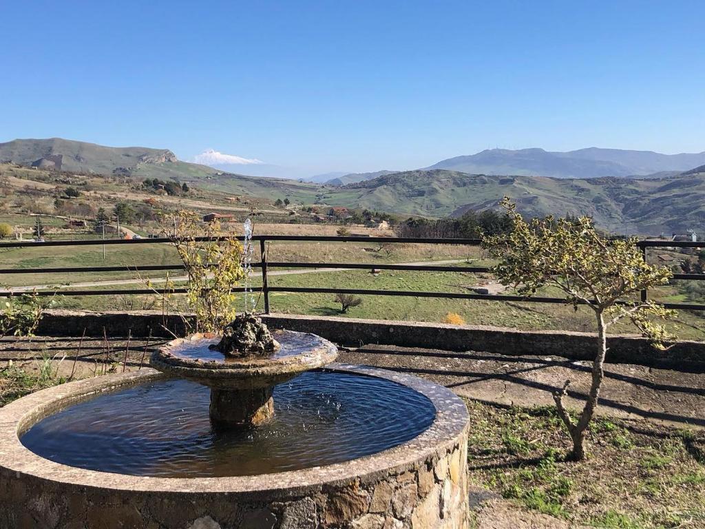 une fontaine dans un champ avec des montagnes en arrière-plan dans l'établissement Rifugio SHIVA, à Petralia Soprana