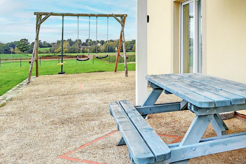 - une table de pique-nique bleue à côté d'une aire de jeux avec balançoire dans l'établissement Gite Baie Du Mont Saint Michel, à Saint-James