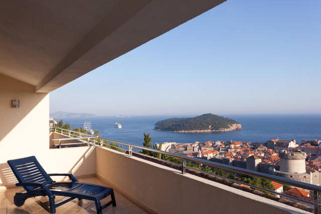 a blue chair sitting on a balcony looking at the ocean at Apartments Simic in Dubrovnik