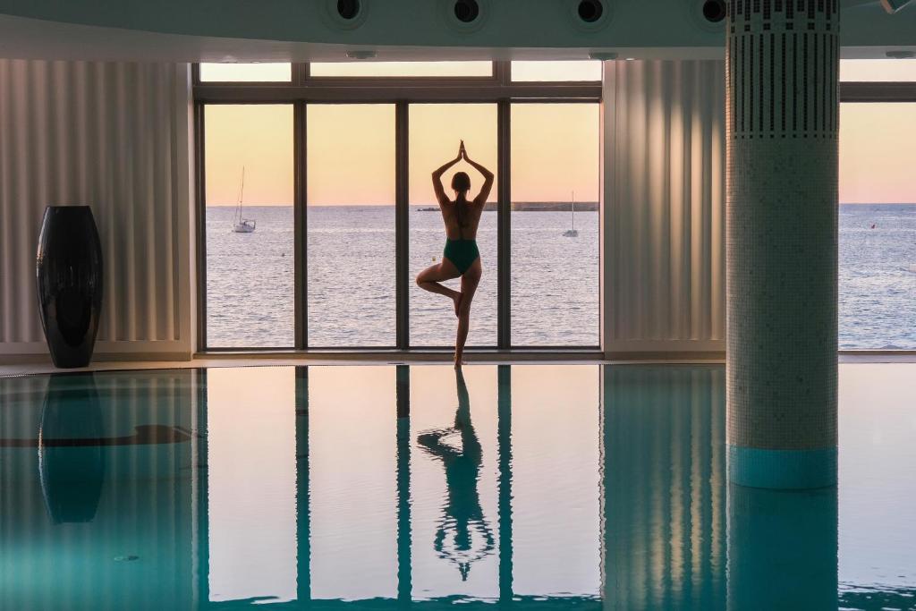 une femme faisant une pose de yoga à côté d'une piscine dans l'établissement Thalazur Saint Jean de Luz - Hôtel & Spa, à Saint-Jean-de-Luz