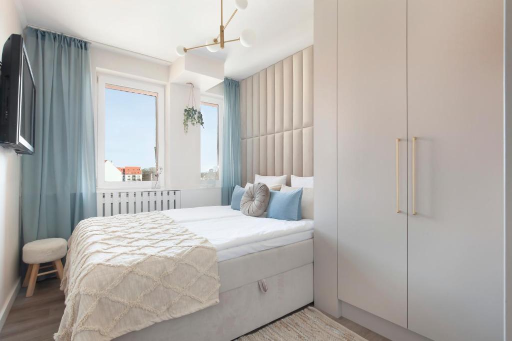 a white bedroom with a bed and a window at Elite Apartments Sandy in Gdańsk