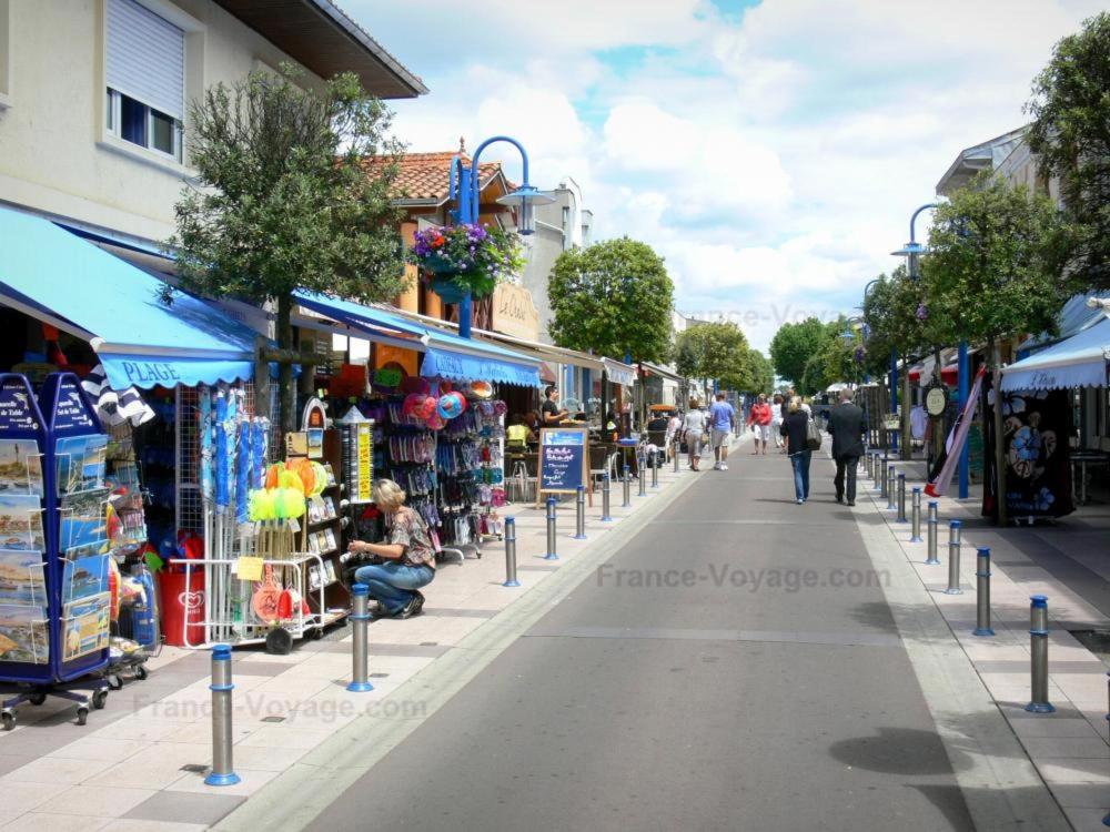 a street with shops and people walking down a street at Andernos-Maison de centre-ville avec jardin in Andernos-les-Bains