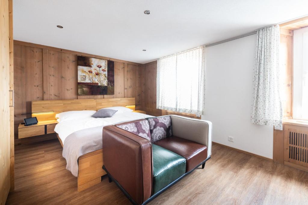 1 dormitorio con 1 cama y silla de cuero en La Tgoma - Hotel & Restaurant, en Lenz