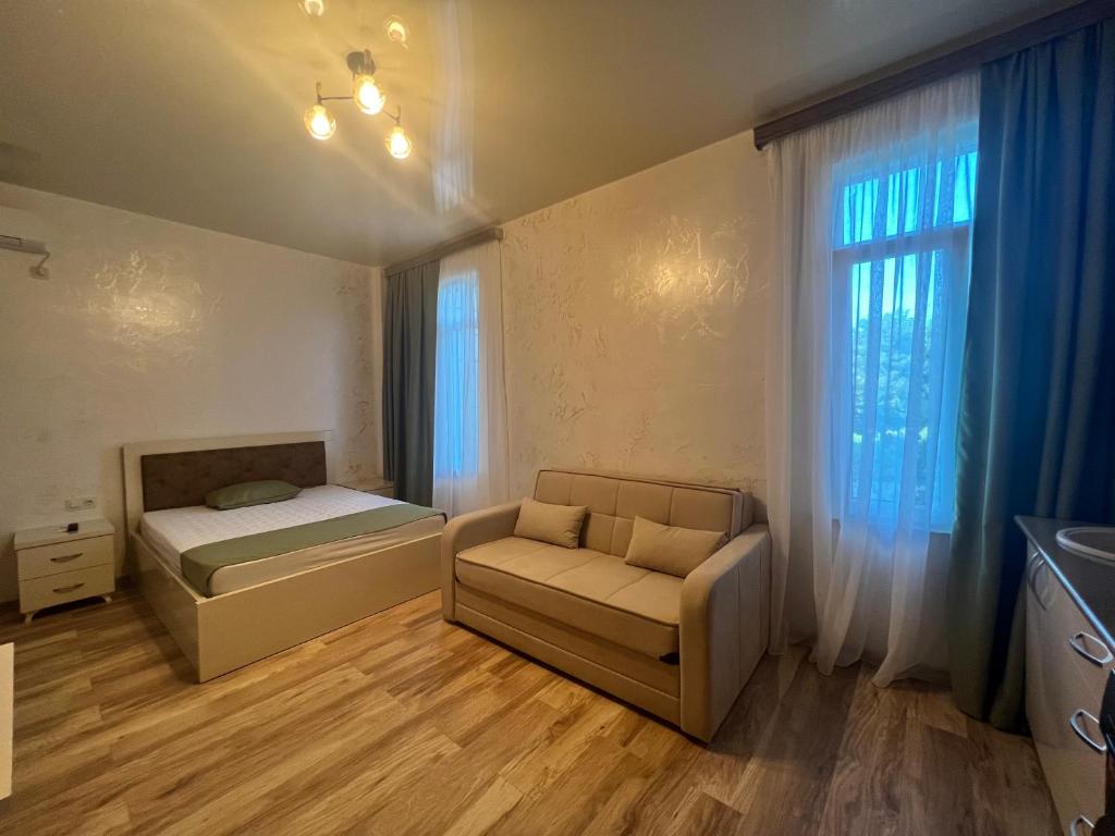 a bedroom with a bed and a couch and a window at Apartments NITA in Batumi