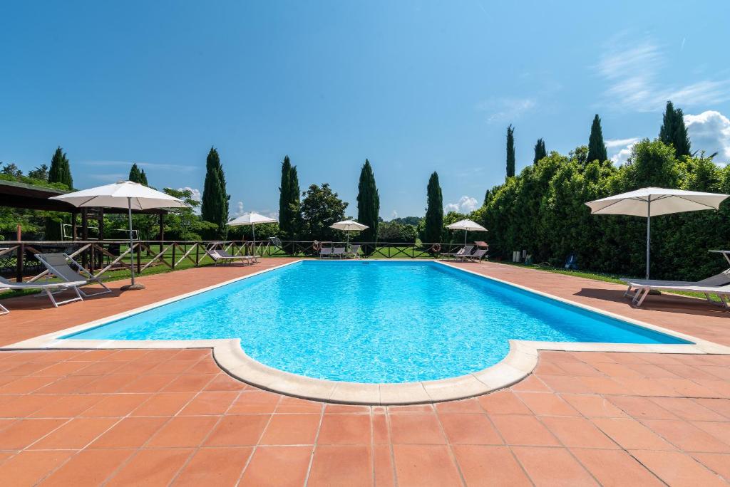ein großer Pool mit Stühlen und Sonnenschirmen in der Unterkunft Appartamento Fattoria in Laterina