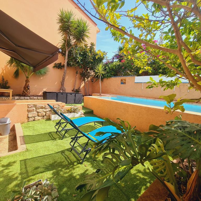 une cour avec deux chaises et une piscine dans l'établissement Villa standing 10 personnes piscine/ pinède, à Canet