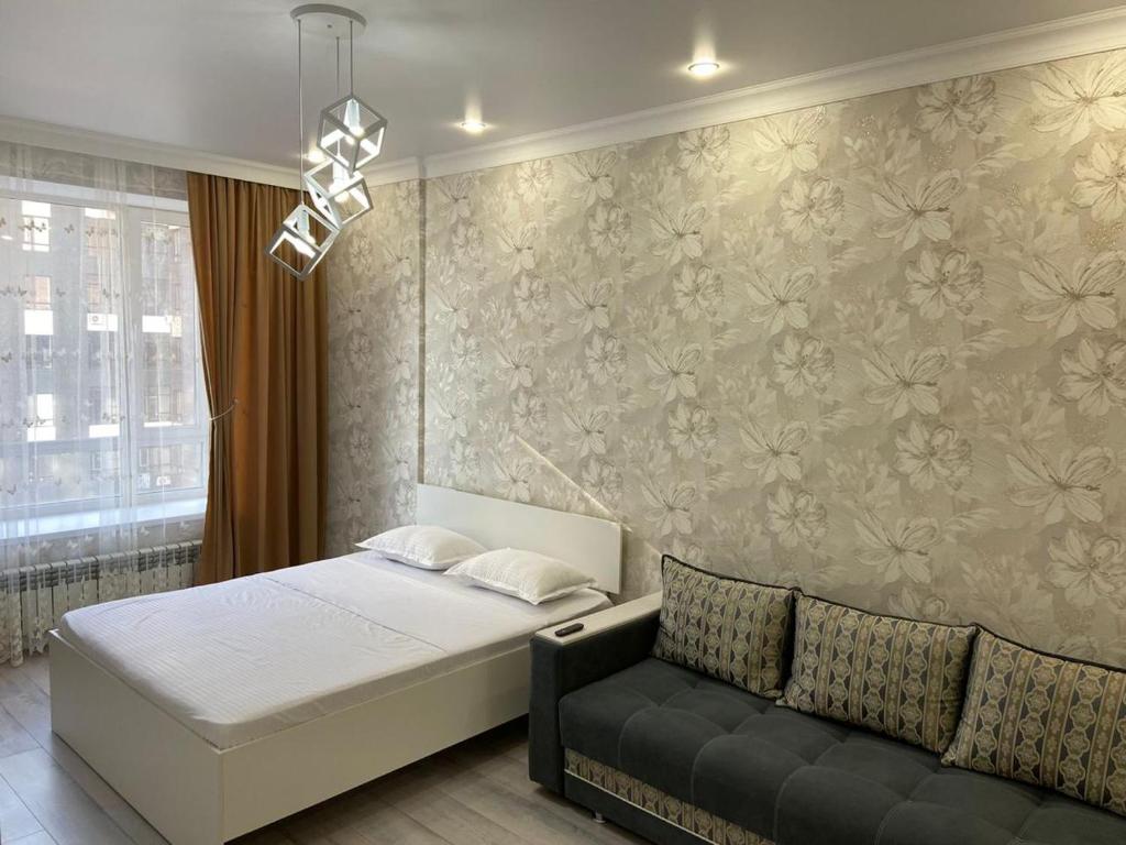 um quarto com uma cama e um sofá em Эксклюзив-404 em Astana