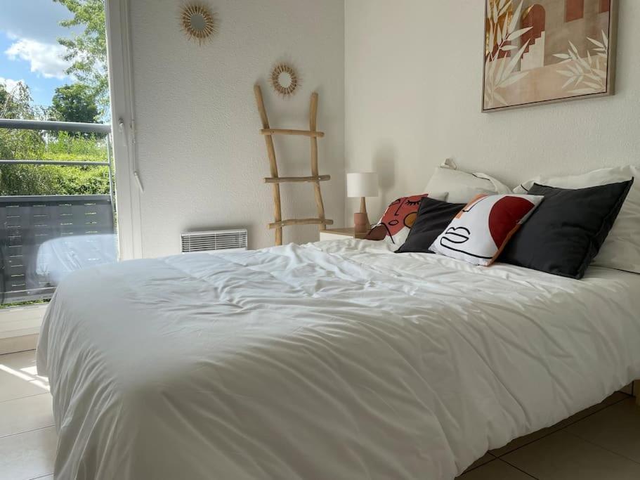 uma cama branca num quarto com uma janela em Appartement T3, Terrasse, Piscine, 2 Places Parking Privé em Onet le Château