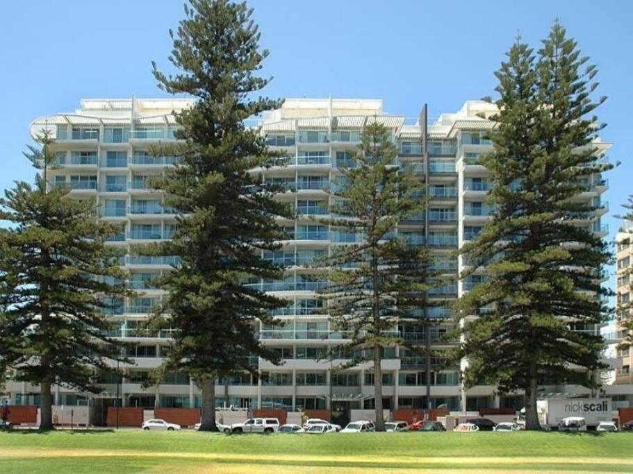 two trees in front of a large building at Liberty bay holiday Spacious two bedroom, two bathroom with sea views in Glenelg