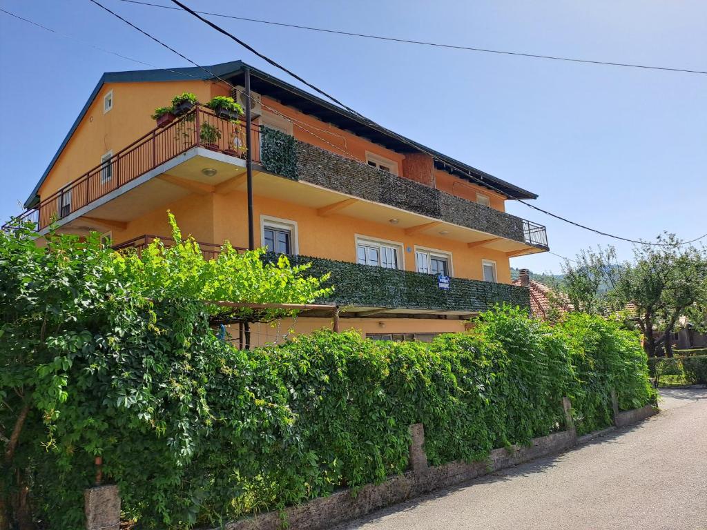 a yellow house with a hedge in front of it at Apartments Mirković in Cetinje
