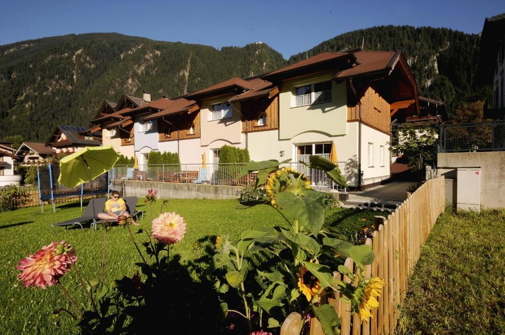una mujer sentada en el césped frente a una casa en Chalet Helene en Mayrhofen