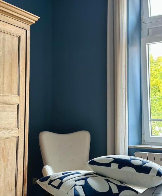 a blue room with a chair and a window at Maison Comtale in Rochefort