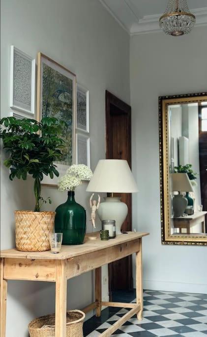 a room with a table with a lamp and a mirror at Maison Comtale in Rochefort