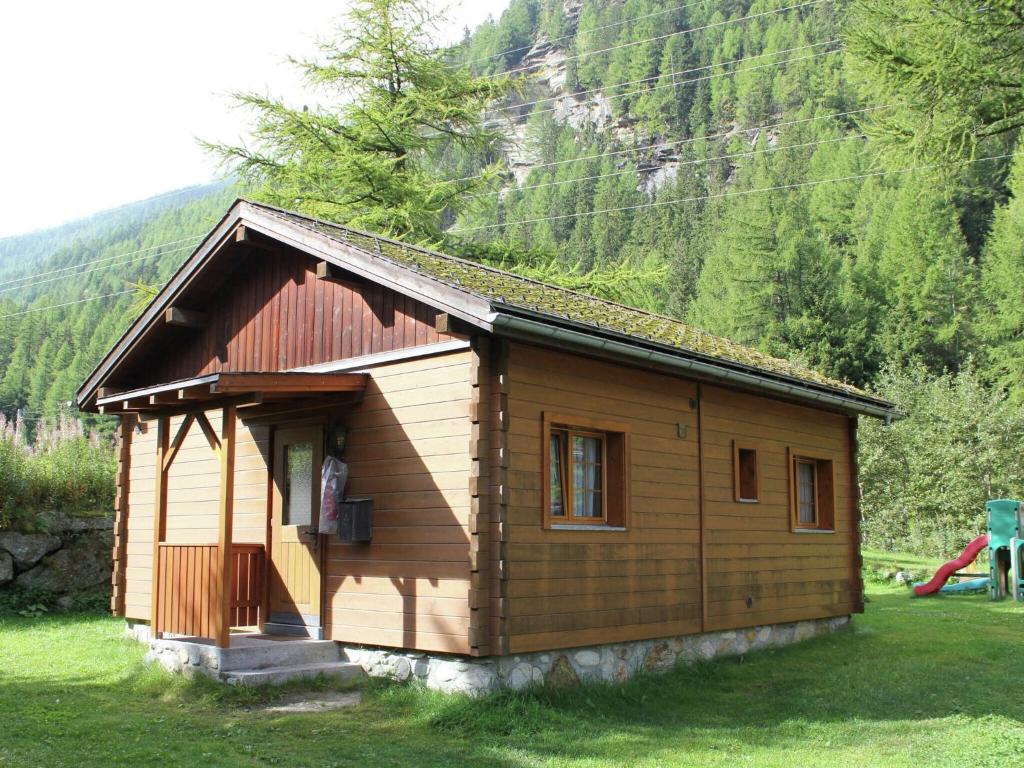 una pequeña casa de madera en un campo con una montaña en Modern Chalet in Saas Balen with Garden en Saas-Balen