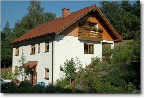 uma pequena casa branca com um telhado de madeira em Ferienwohnungen Röller em Rinnthal