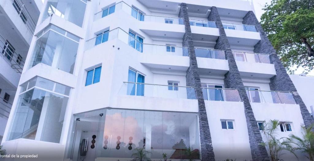 um edifício branco com palmeiras em frente em Samaná Suites Hotel em Santa Bárbara de Samaná