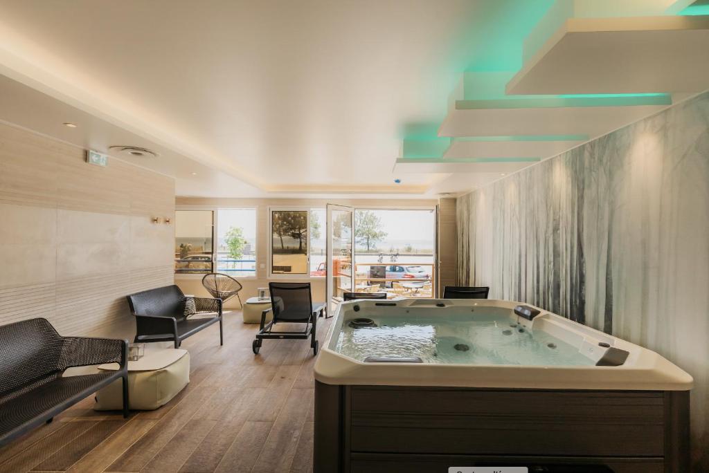 een grote badkamer met een groot bad in een kamer bij Hôtel Édenia - Spa Estime&Sens in Carnac