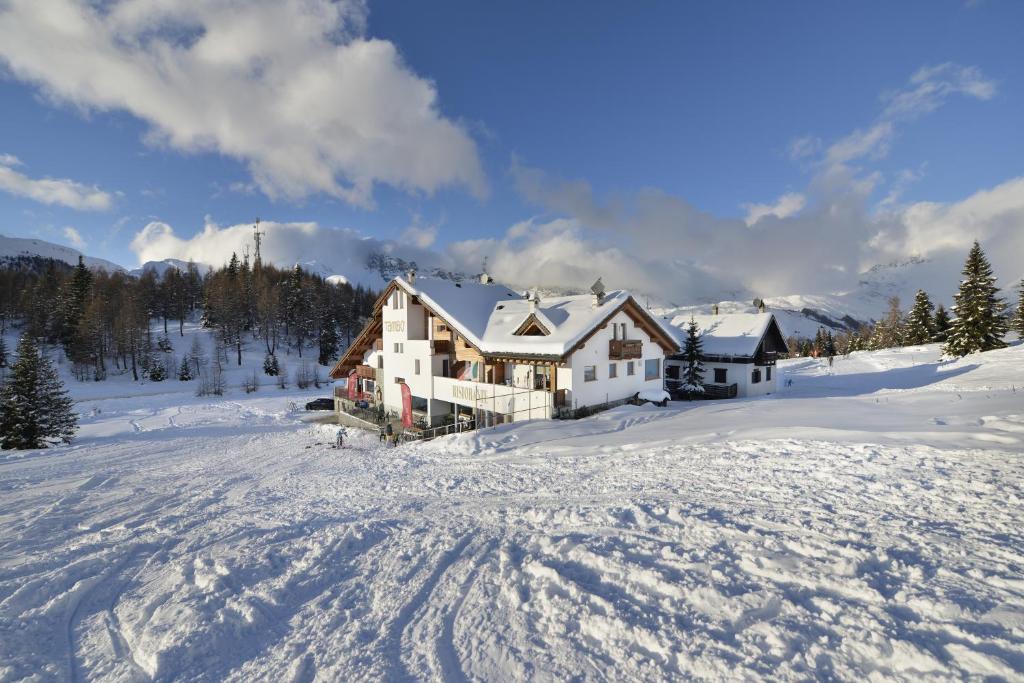 une maison dans la neige dans un champ enneigé dans l'établissement Hotel Tambò, à Campodolcino