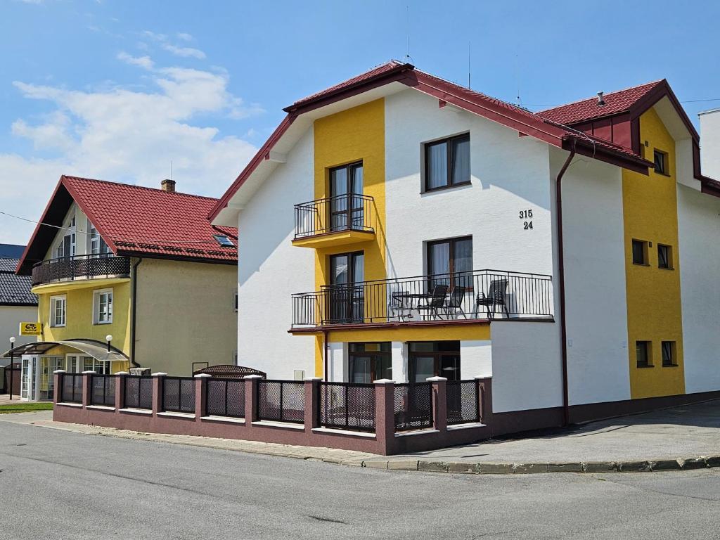 a white and yellow building on the side of a street at Comenius Apartments - Apartmány na rohu in Svidník