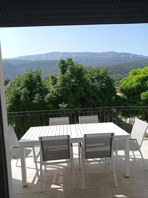 une table blanche et des chaises sur un balcon dans l'établissement LA MAISON DE PAPOU La Vigne A NANS LES PINS 83860, à Nans-les-Pins