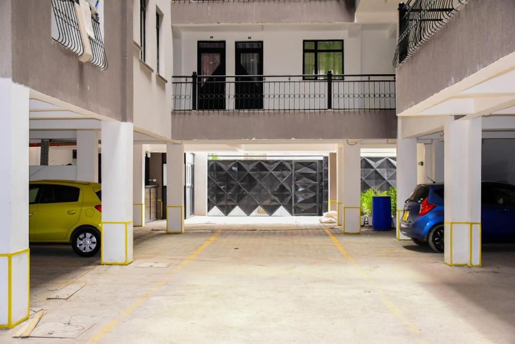 a parking lot with two cars parked in front of a garage at Immaculate 1-Bed Apartment in Nairobi in Nairobi