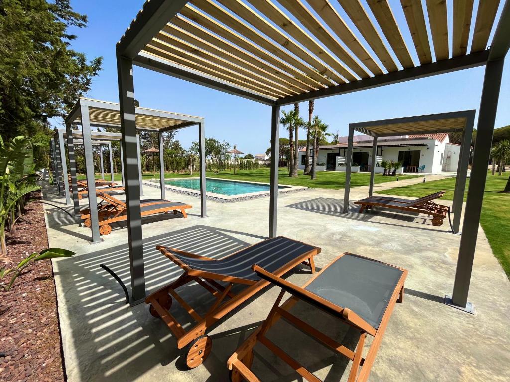 a group of chairs under a pavilion next to a pool at Alojamiento rural FINCA AZUCENA SUITE in Conil de la Frontera