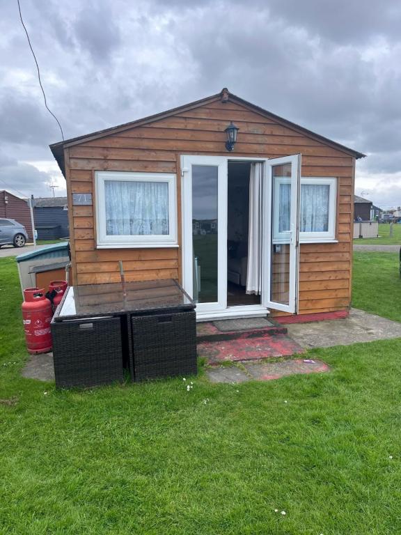 a tiny house in a yard with a porch at Chalet 71 in Leysdown-on-Sea