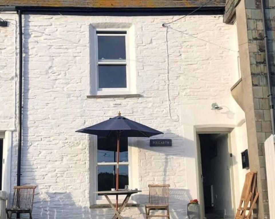 a table with an umbrella in front of a building at Polgarth in Port Isaac